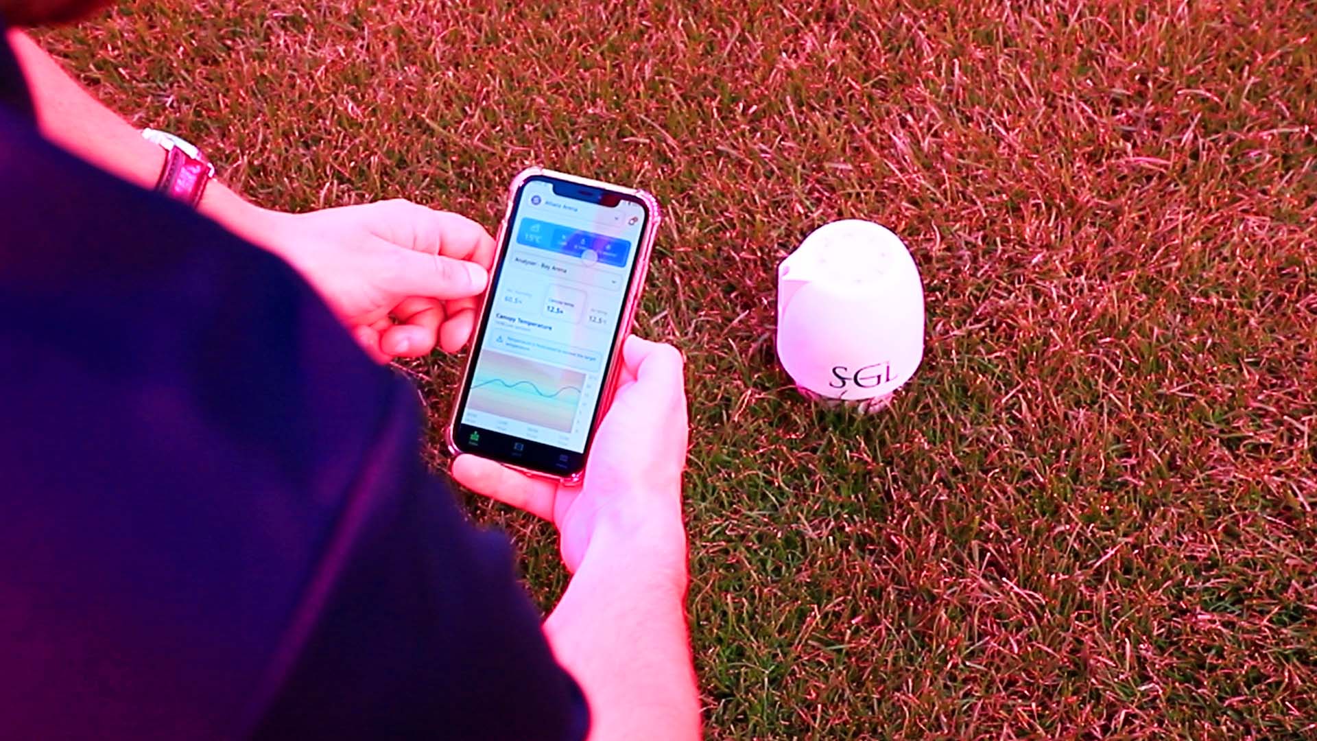 A grounds manager checking data on the SGL Portal with the SGL TurfPod in the background for efficient use of grass grow lighting technology.